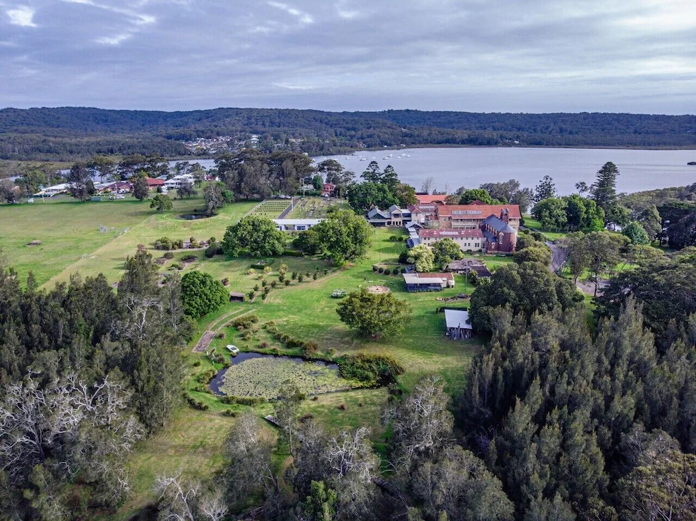 Aerial view of Mary MacKillop Spirituality Centre, showing its buildings, gardens and surrounding bushland beside the Kincumber Broadwater.